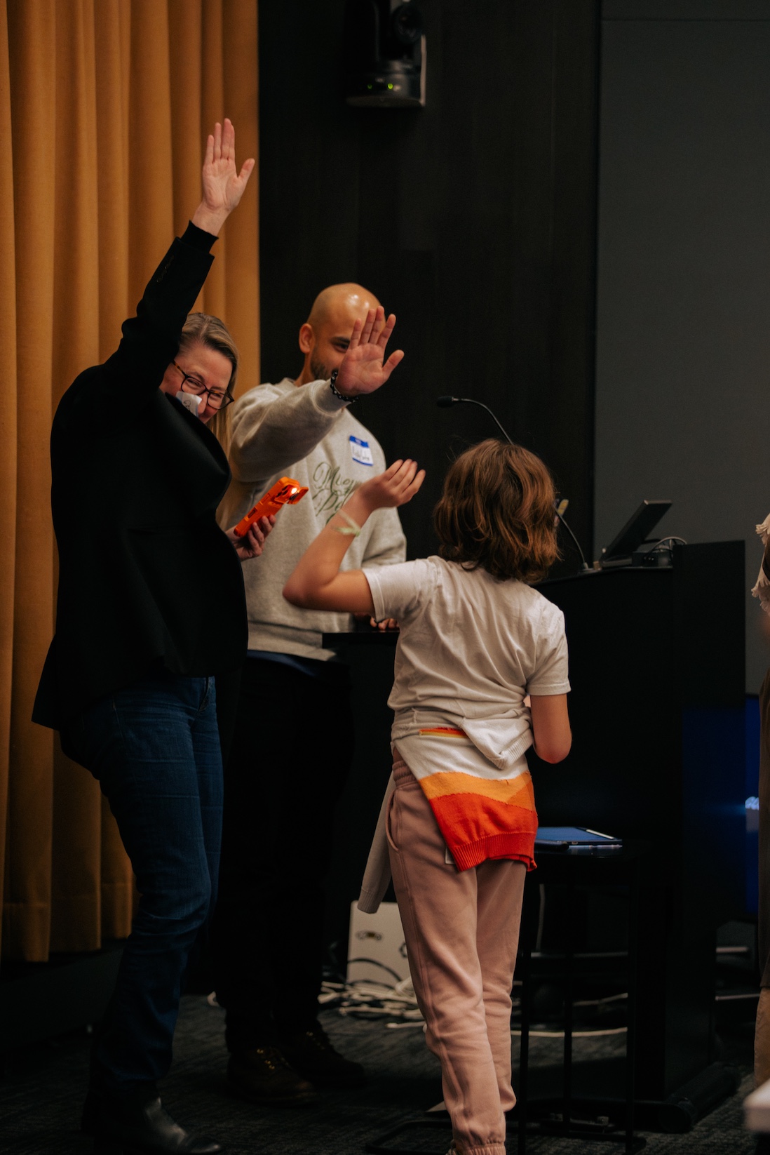back view of a child high fiving a woman on stage